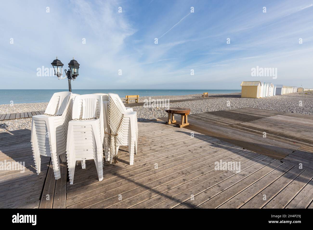 Chairs stacked at the foot of a lamppost on the edge of a pebble beach in Cayeux-sur-Mer. Opal Coast, France Stock Photo