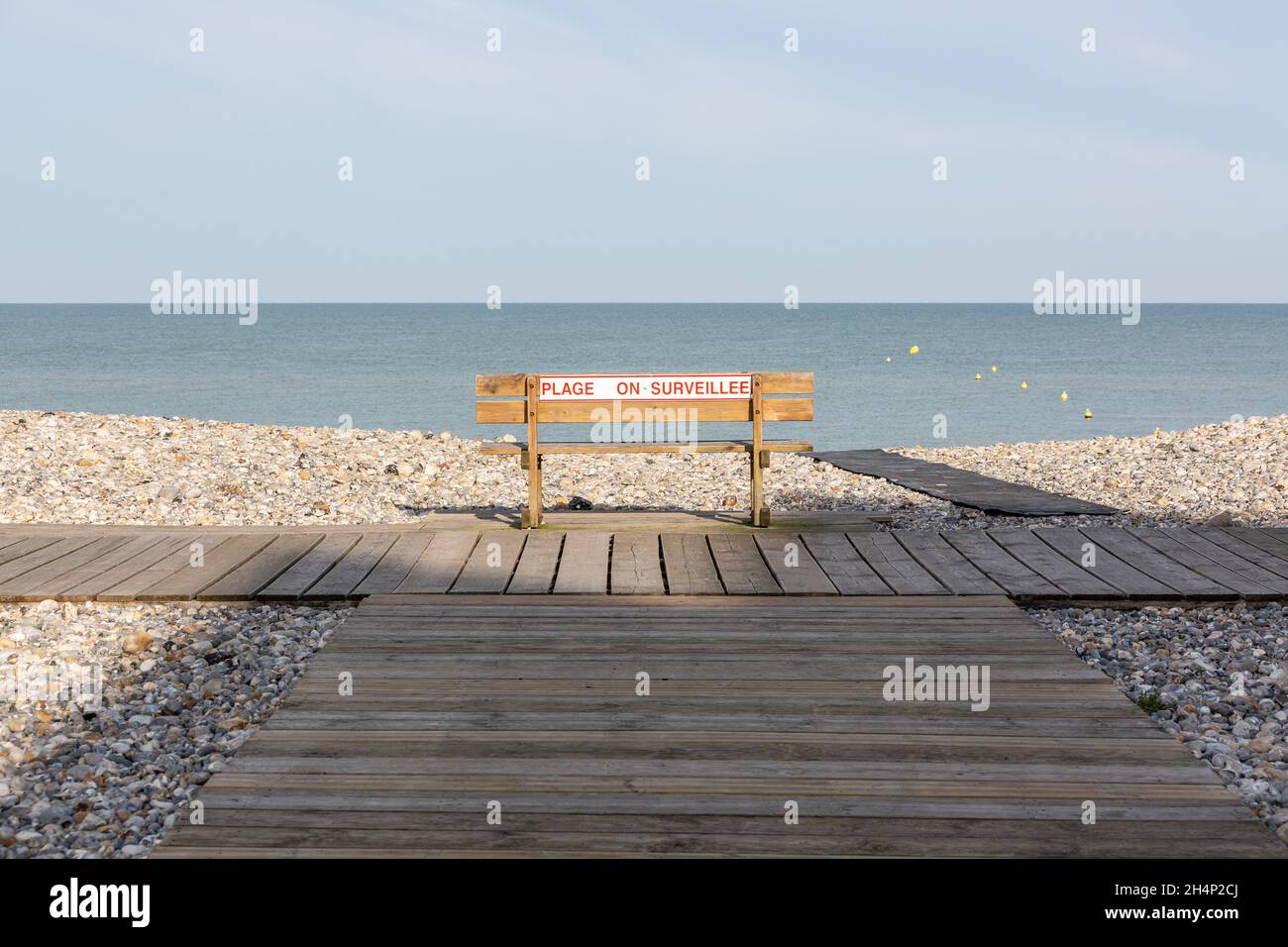 Lonely public bench on a pebble beach in Cayeux-sur-Mer. Opal Coast, France Stock Photo
