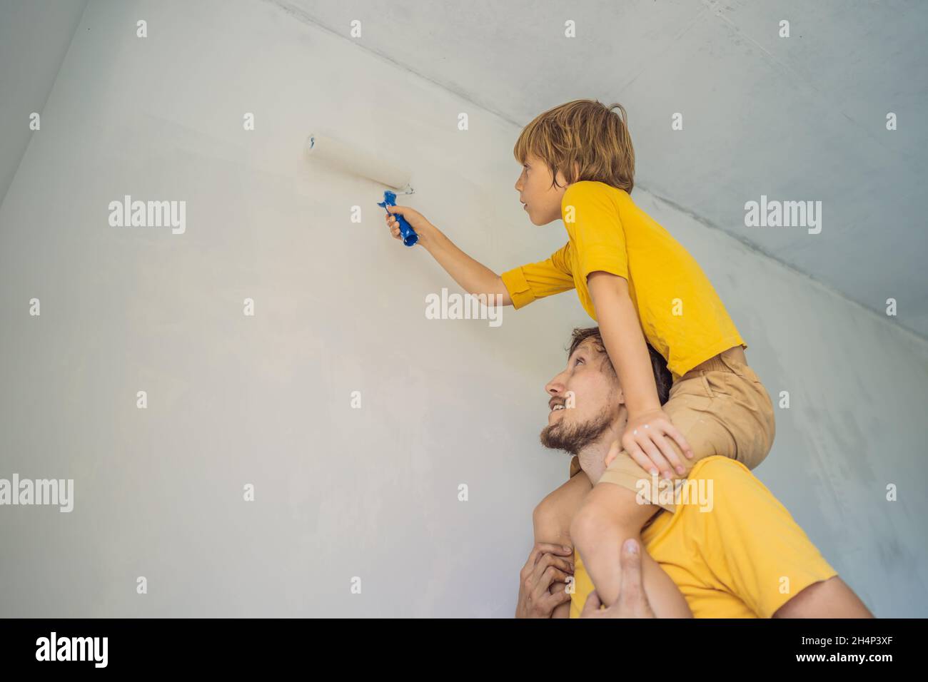 Father and son painting a wall in their home do it in the course of ...