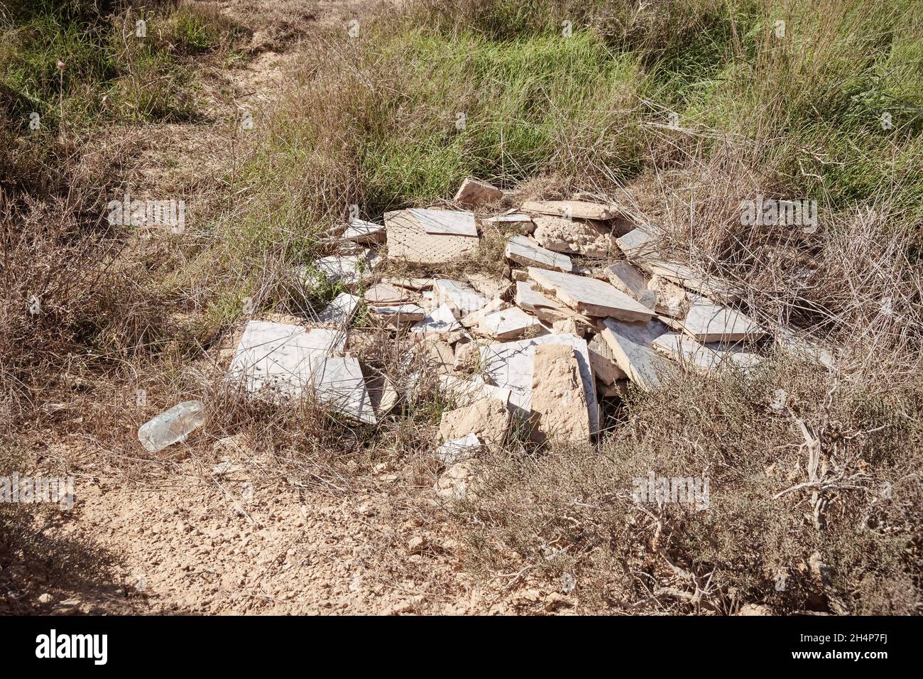 wantonly discarded building materials and a plastic bottle that were dumped illegally pollute a nature reserve in the Negev Highlands desert in Israel Stock Photo