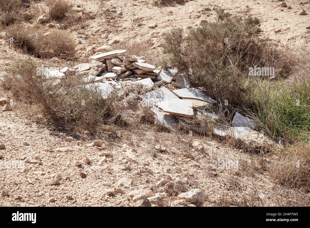 irresponsibly discarded building materials that were dumped illegally pollute a small protected stream bed in the Negev Highlands desert in Israel Stock Photo