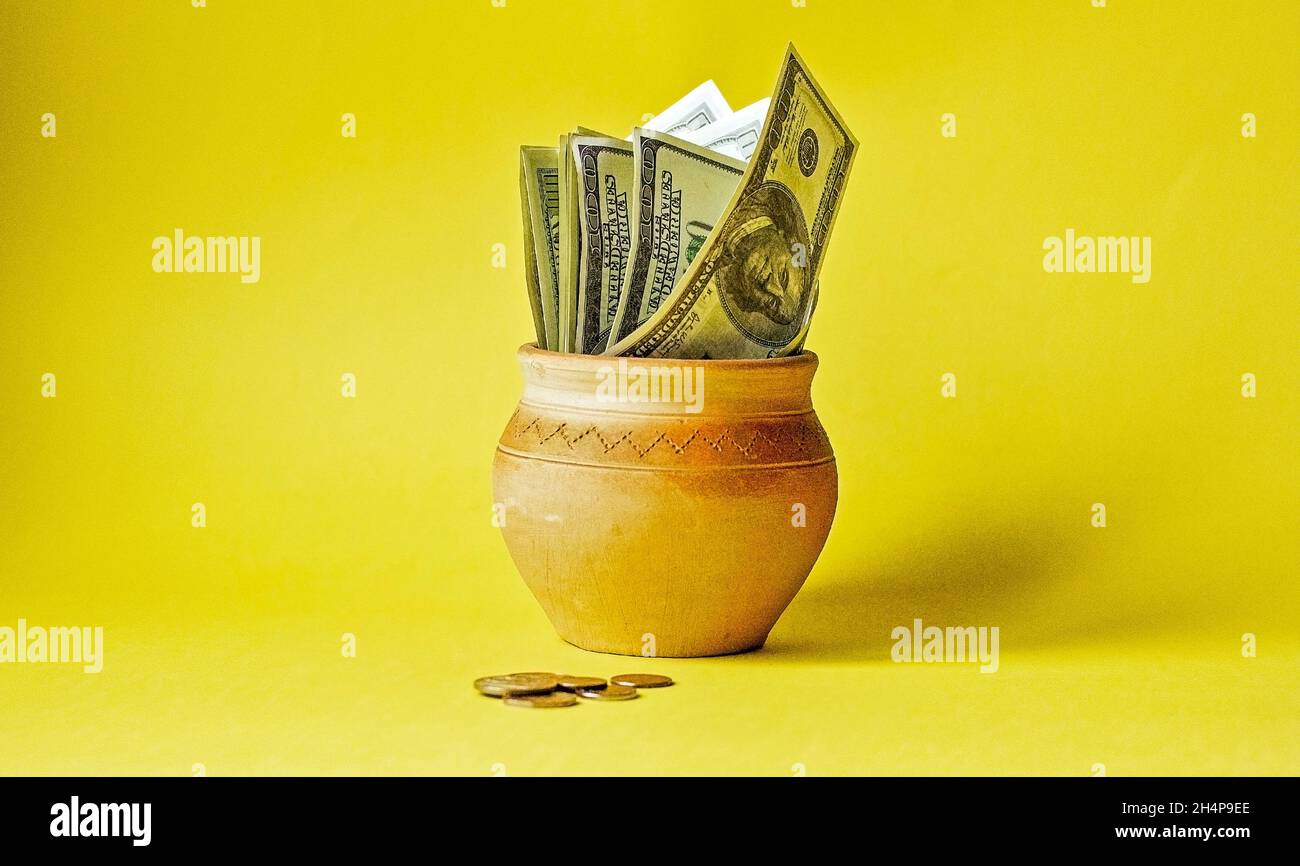 Pot full of US cash on a yellow background Stock Photo
