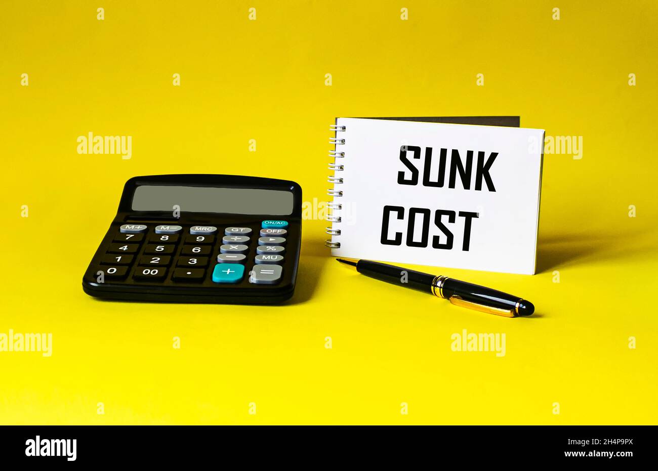 Notepad with calculator, pen and writing on the notepad SUNC COST Stock Photo