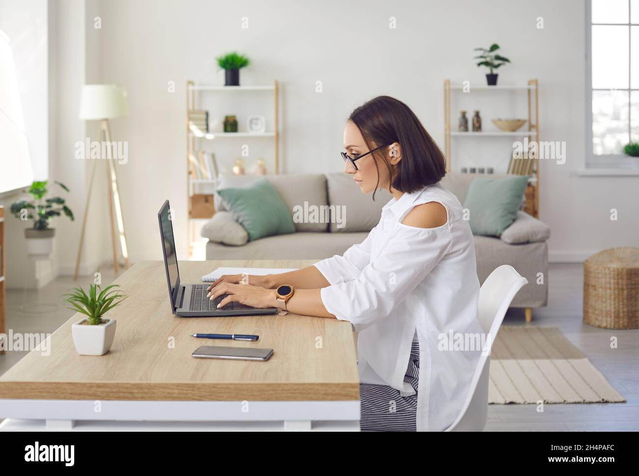 Serious, focused and dedicated woman doing business project on laptop in her home office. Stock Photo
