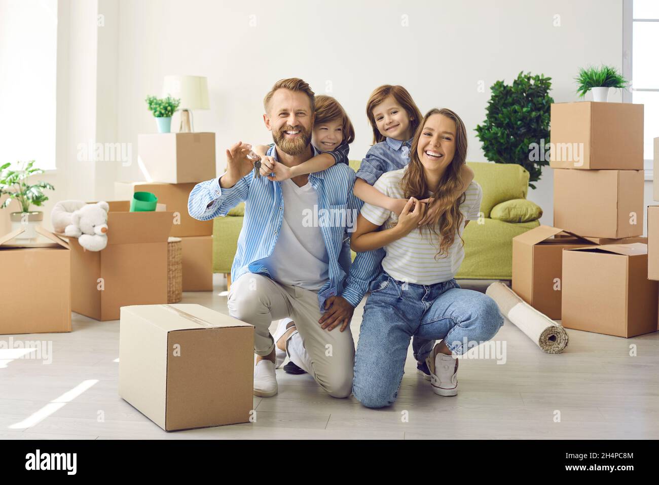Happy excited family smiling and showing the keys to their new house or ...