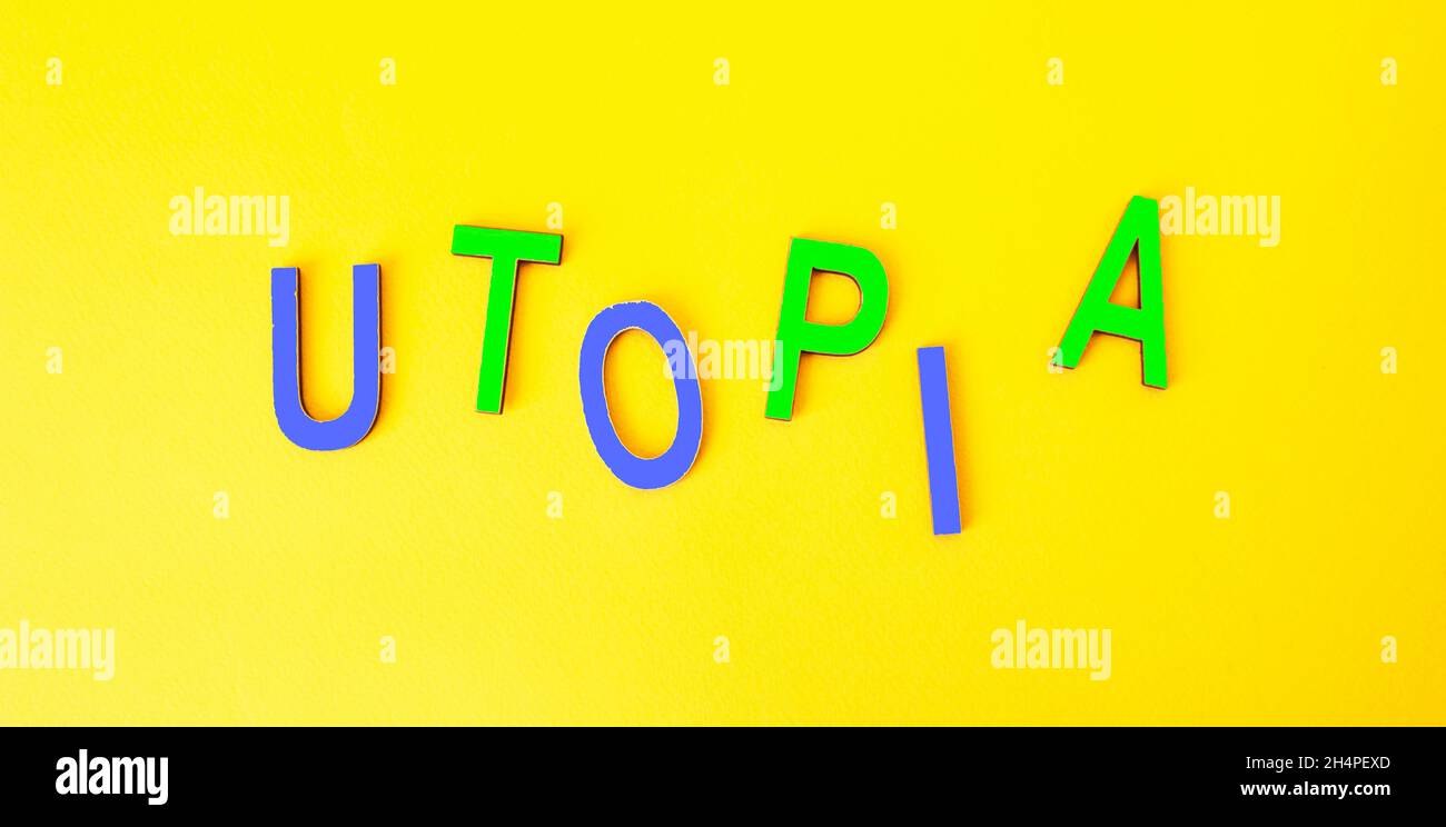 the word UTOPIA consists of wooden multicolored letters on a yellow background Stock Photo