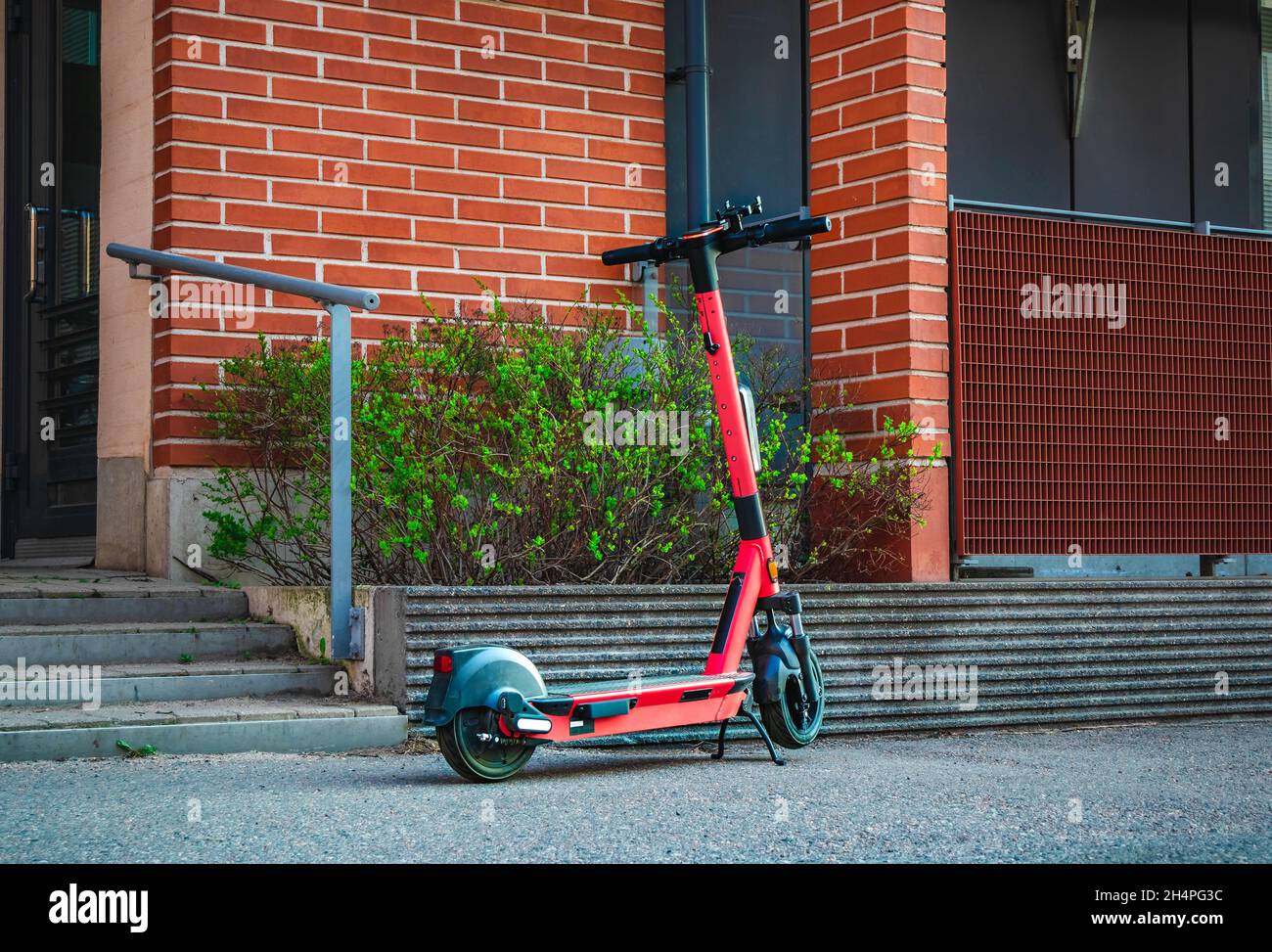 Electric kick scooter for rental parked on sidewalk of street in front