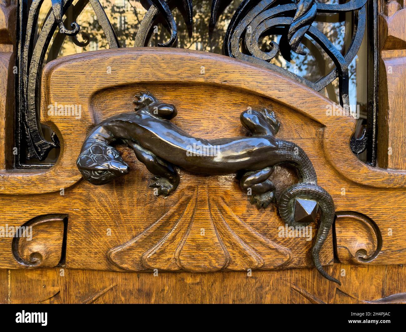 Ornate art nouveau wooden door detail with a bronze figurine of a lizard shaped door handle, Paris, France Stock Photo