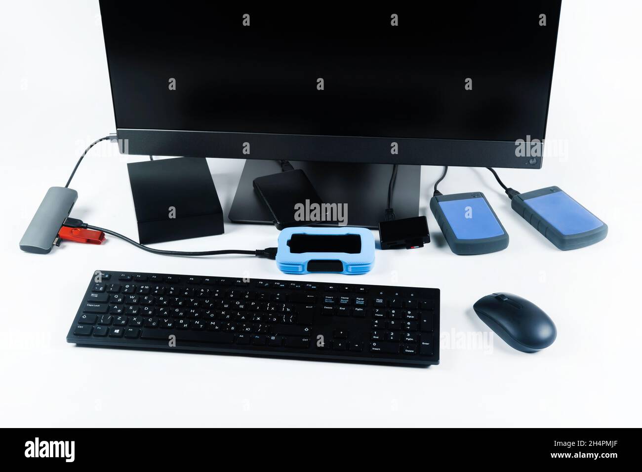 Multiple external hard drives connected to a monoblock on a white with hard