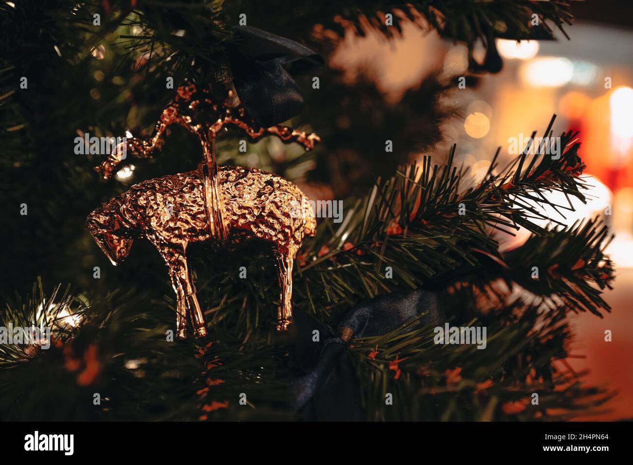 Christmas toy golden lamp hanging on the Christmas tree with blurry shiny festive bokeh lights on background. Merry Christmas and Happy New Year 2022 Stock Photo