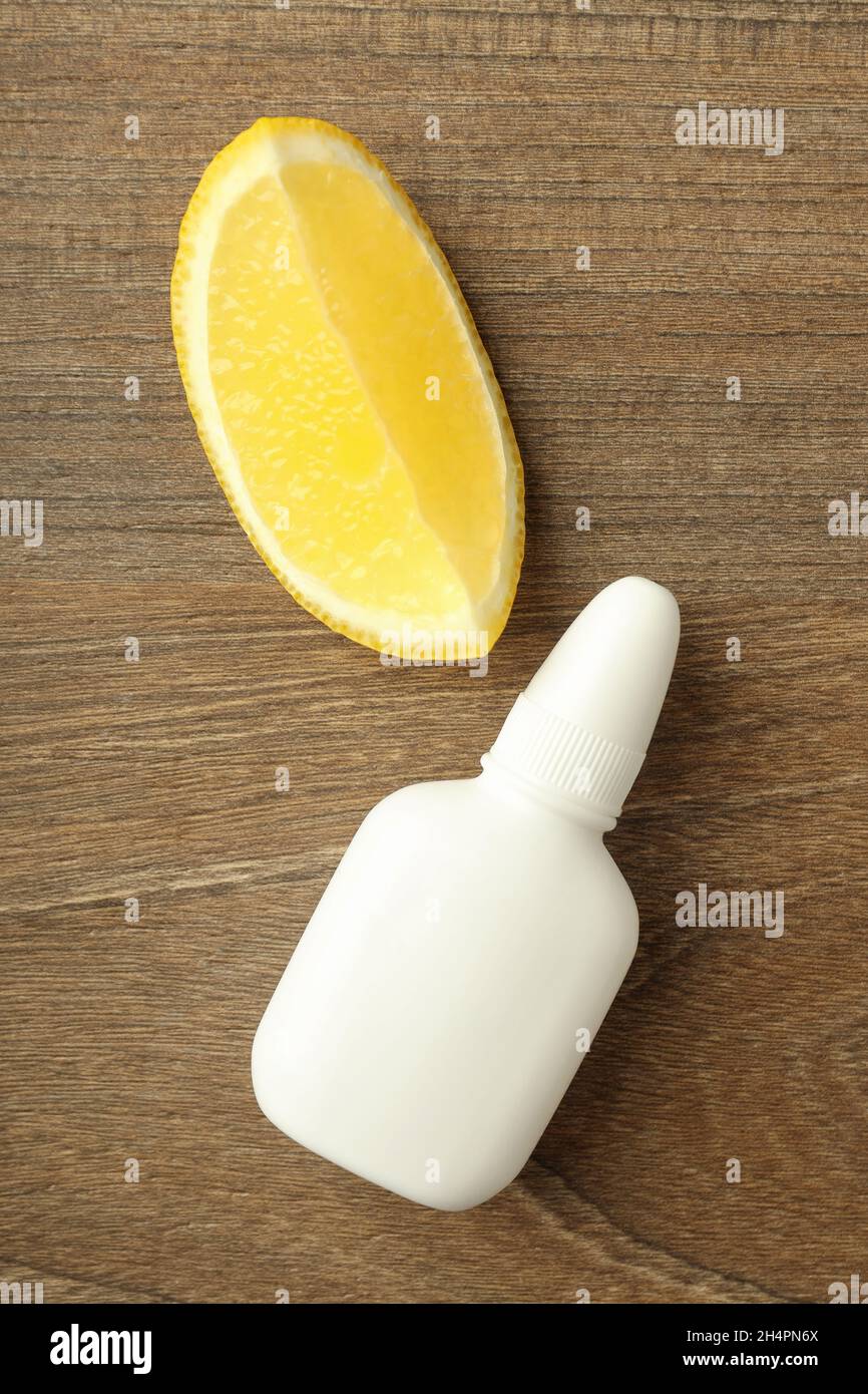 Blank bottle of nasal spray and lemon slice on wooden background Stock Photo