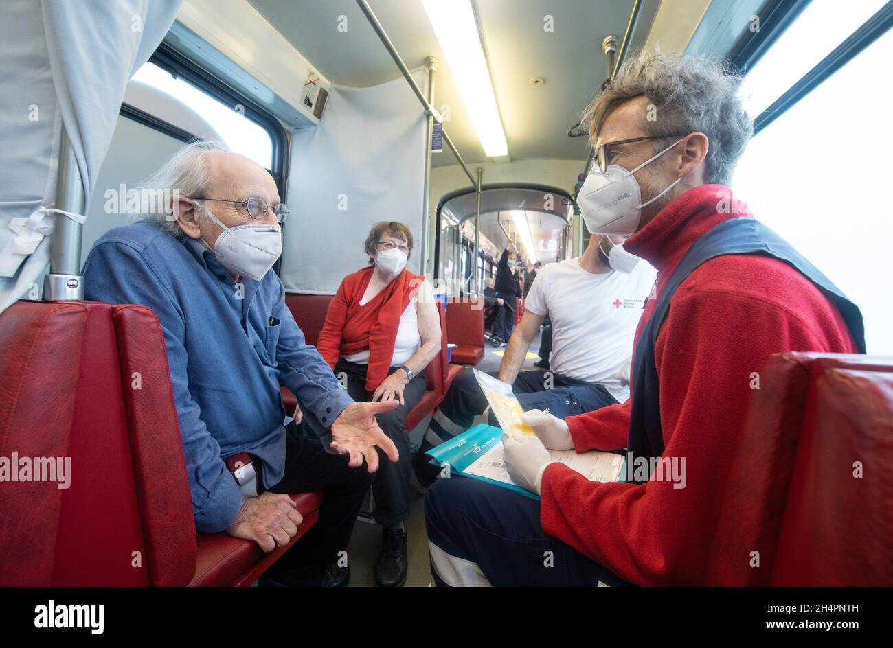 04 November 2021, Hessen, Frankfurt/Main: An 85-year-old man gets information about possible side effects in the 'Impftram' in Frankfurt before his booster vaccination. People who want to be vaccinated can board the tram, which runs on regular routes through Frankfurt, at any time without an appointment. Photo: Boris Roessler/dpa Stock Photo