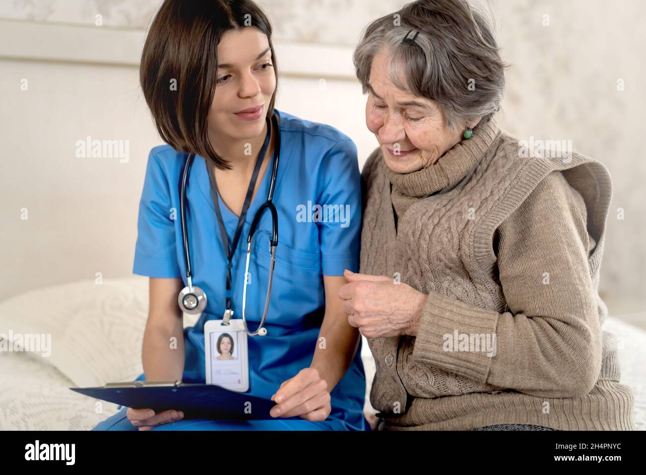 Young nurse is caring for an elderly 80-year-old woman at home,  Stock Photo