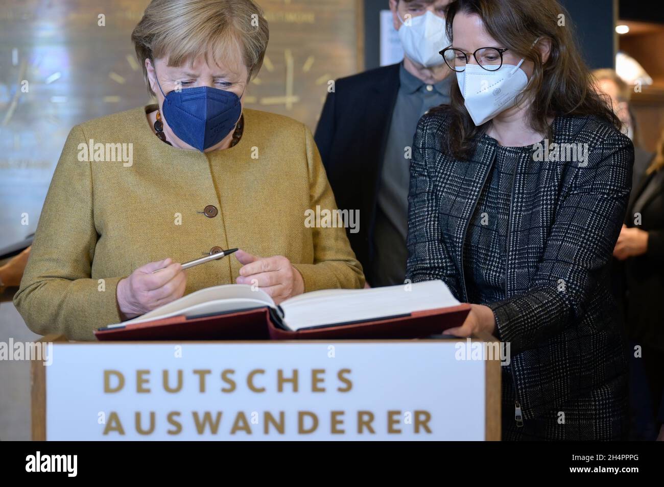 Bremerhaven, Germany. 04th Nov, 2021. The outgoing German Chancellor Angela Merkel (CDU) signs the guest book at the Migration Museum Deutsches Auswandererhaus, on the right Simone Blaschka, director of the museum. The outgoing Chancellor has arrived in Bremerhaven for her farewell visit. Credit: Fabian Bimmer/Reuters Pool X02840/dpa/Alamy Live News Stock Photo