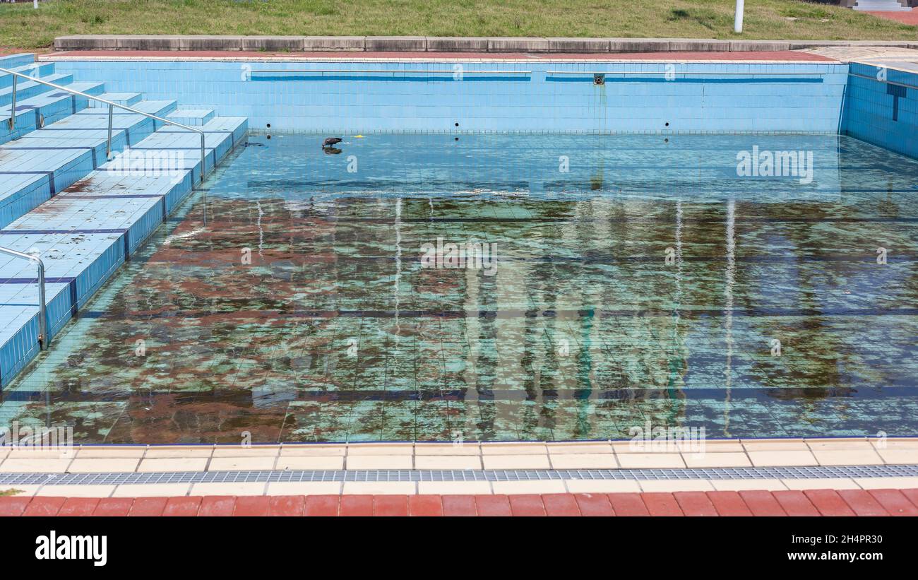 Public swimming pool empty no water dirty no maintenance outdoors public facility. Stock Photo