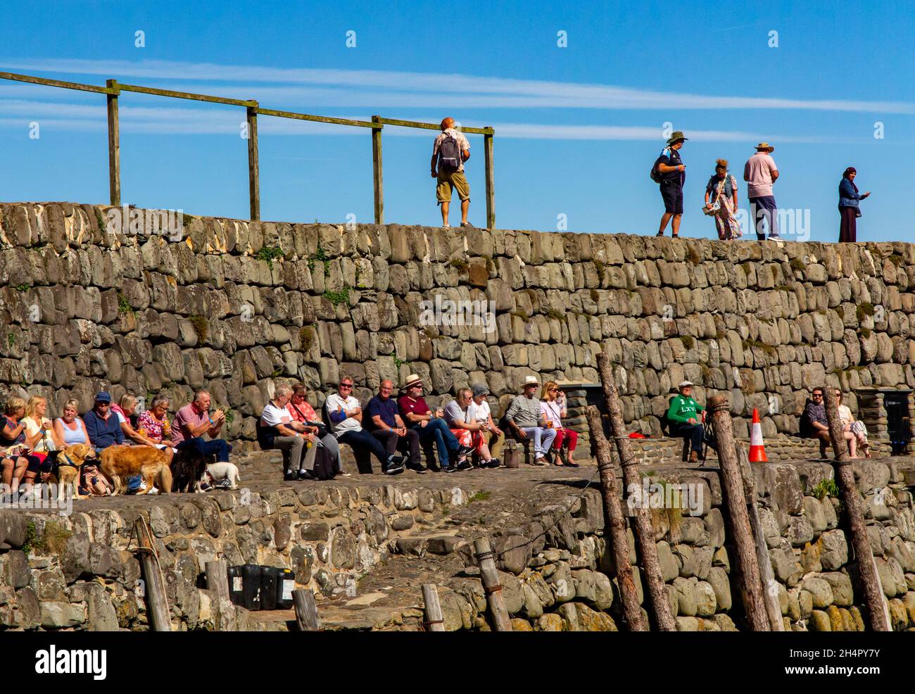 Tourists on the sea wall at Clovelly a harbour village overlooking Bideford Bay and the Bristol Channel in North Devon England UK Stock Photo