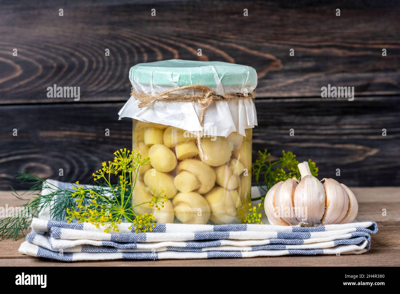 Homemade pickled champignons, garlic in jars on wooden shelf Homemade