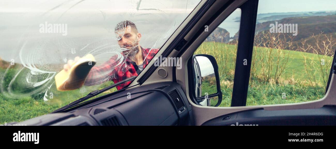 Man cleaning camper van windshield outdoor Stock Photo