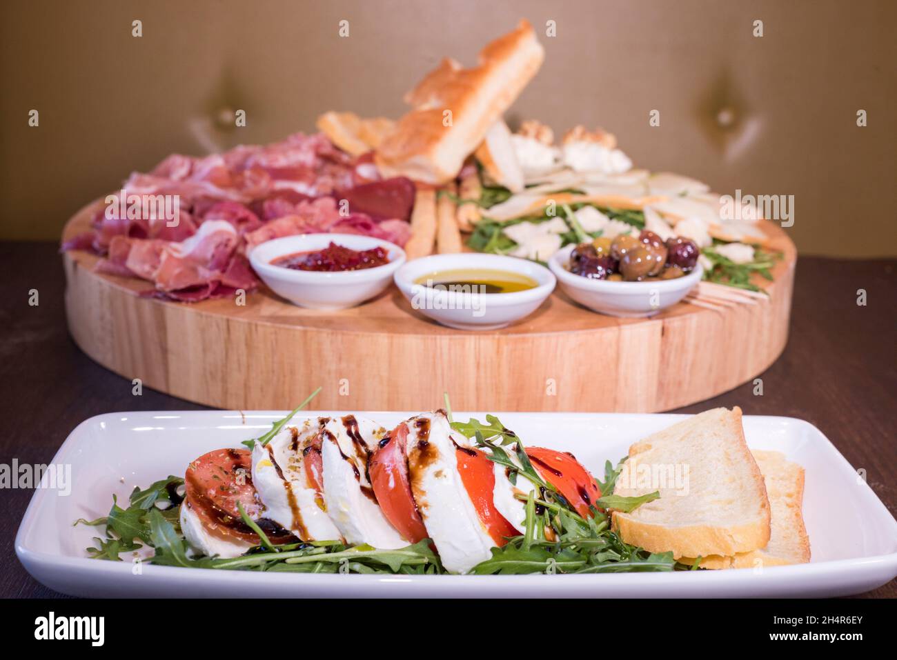 Sheffield, 29 Jan 2018 – mozzarella and tomato starter and a sharing platter of cold meats and cheeses served with bread, olives and salad rocket at V Stock Photo