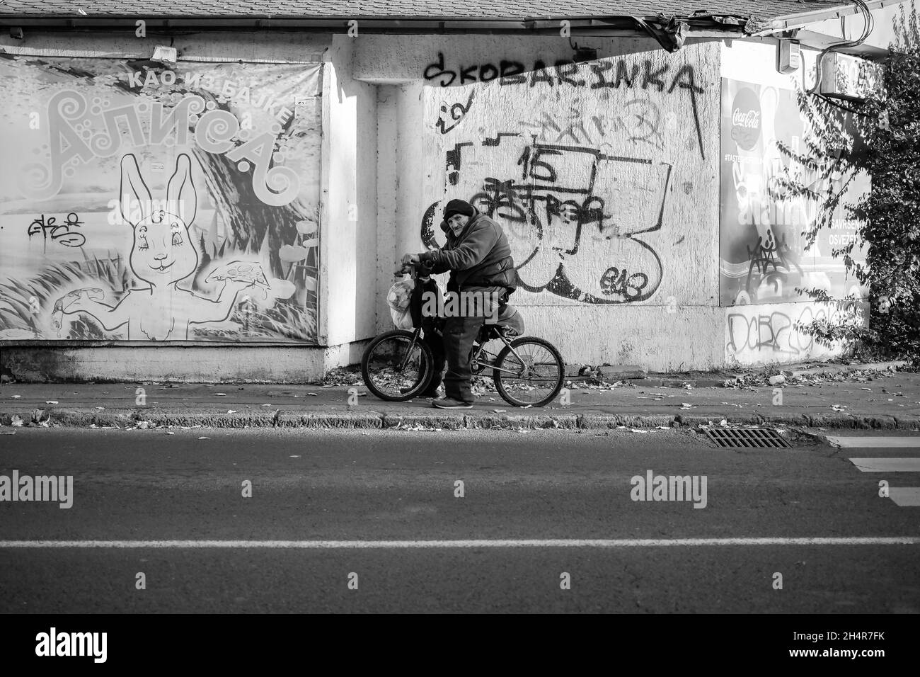 Belgrade, Serbia, Oct 31, 2021: An elderly cyclist resting on the sidewalk (B/W) Stock Photo