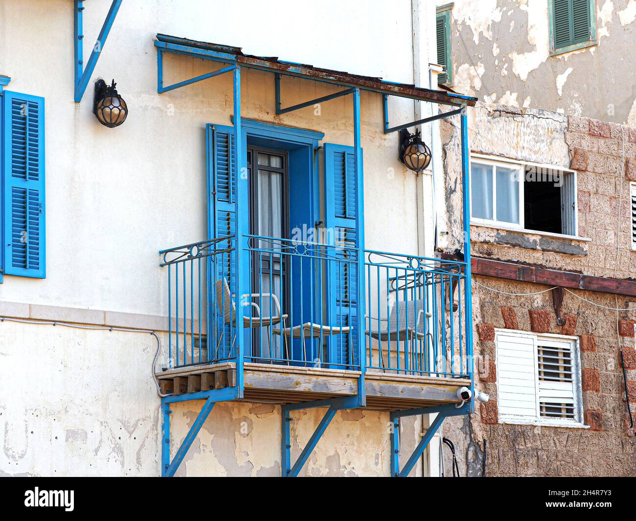 Blue balcony and blue window shutters in a house on the sea Stock Photo