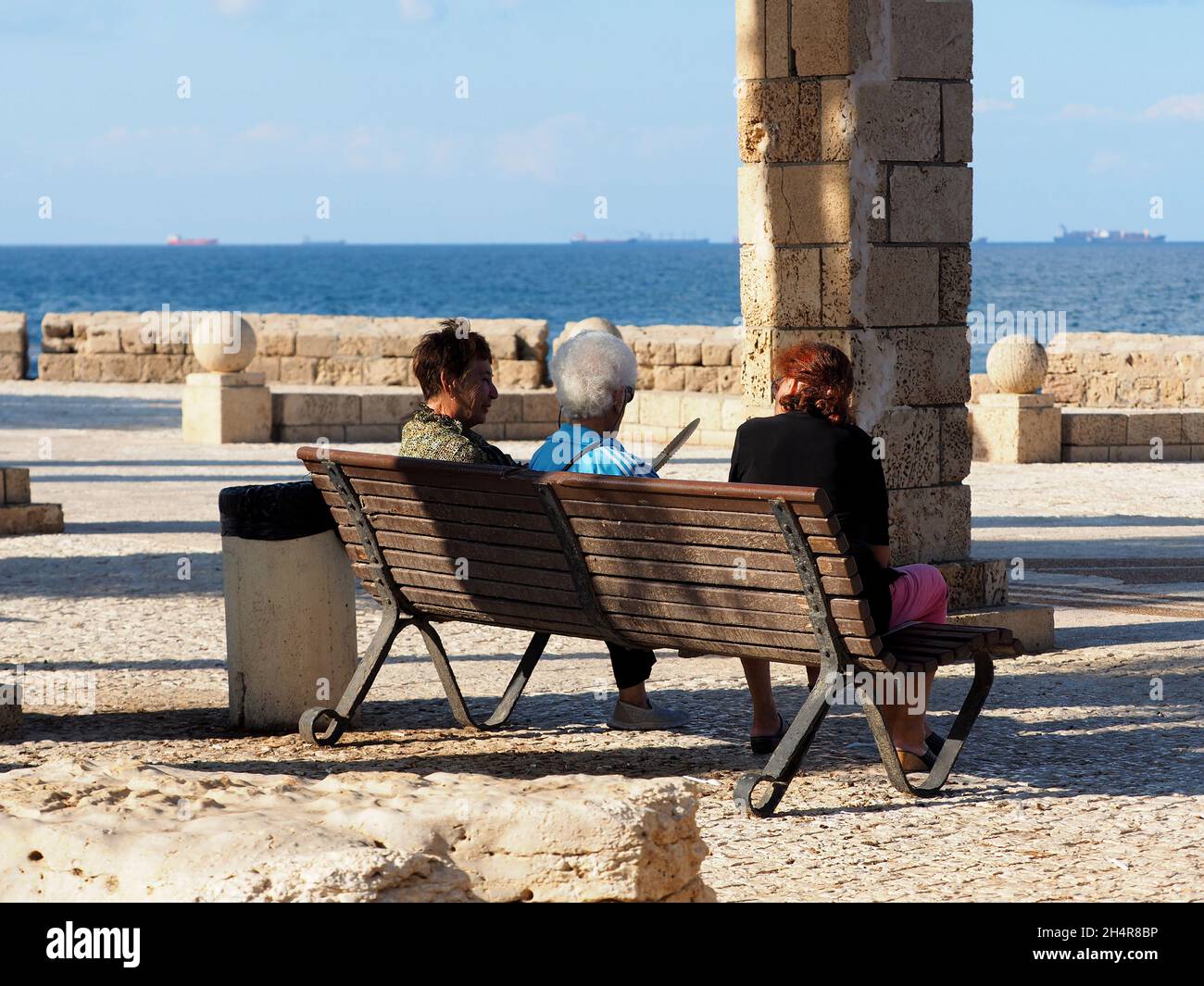 Three elderly women talk on a bench in the city of Akko by the sea. Israel. Stock Photo