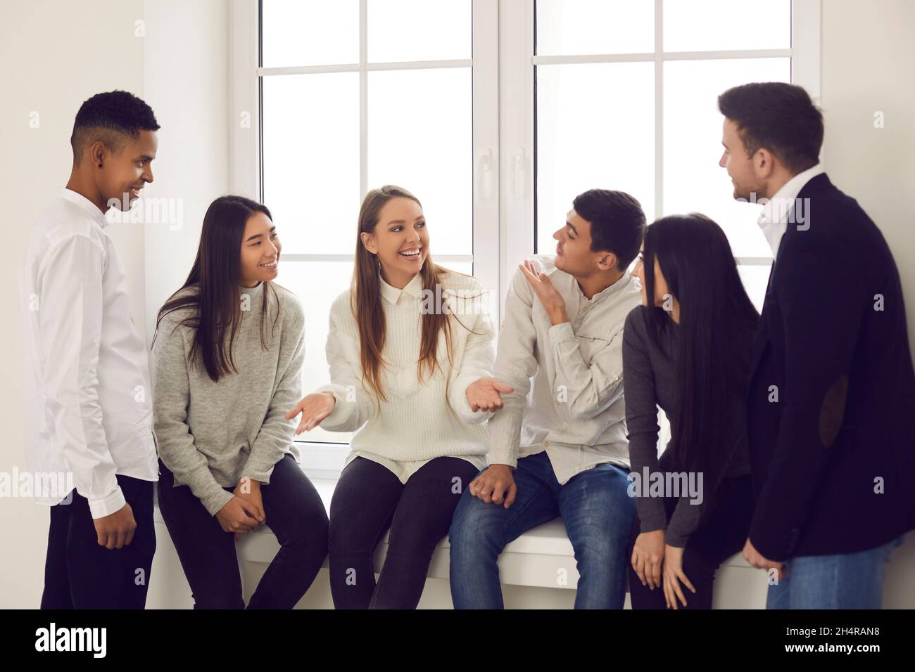 Group of happy young multiracial coworkers or friends talking about funny stuff and smiling Stock Photo