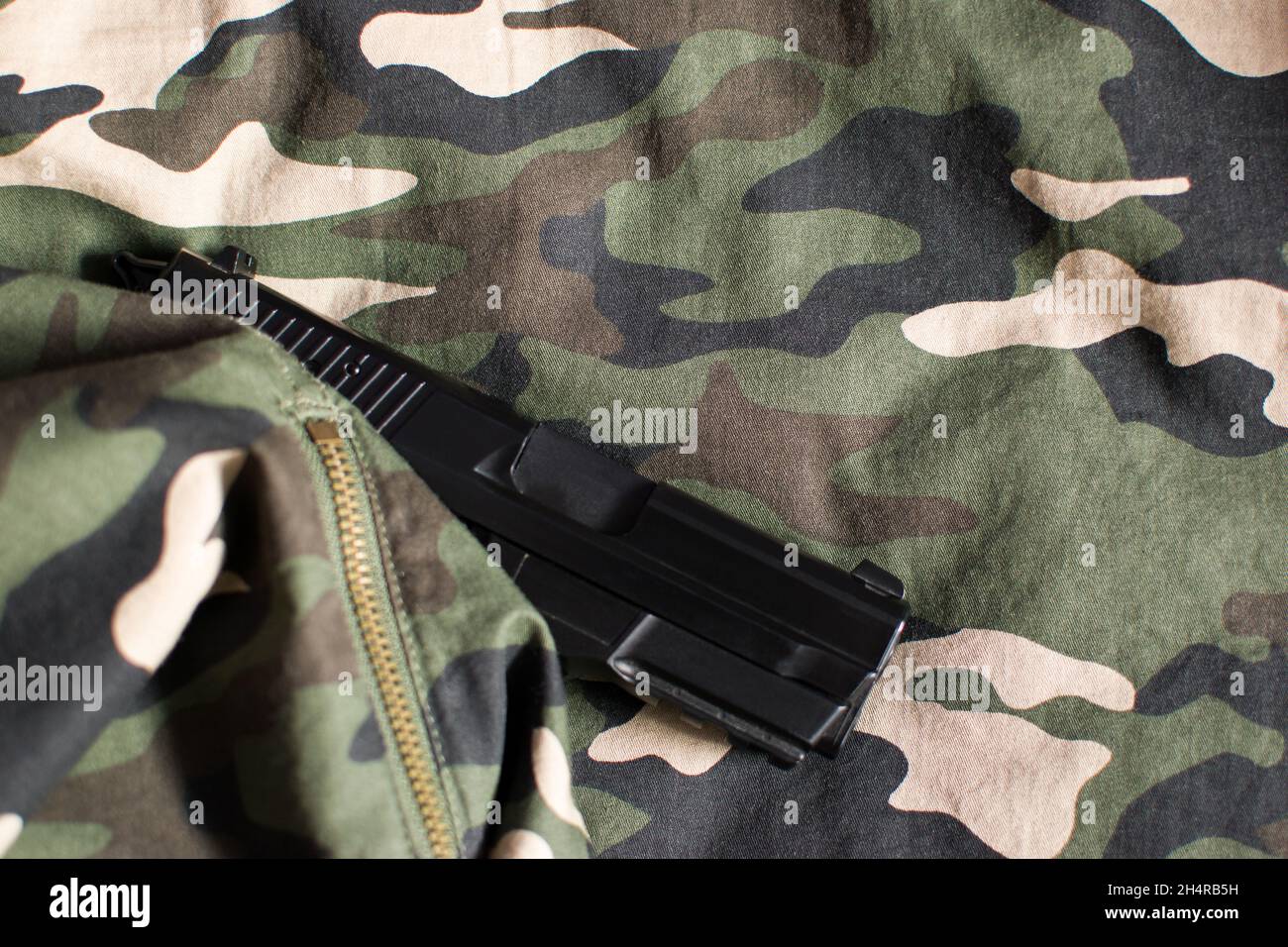 Black handgun, pistol on military black, beige, green and brown uniform Stock Photo