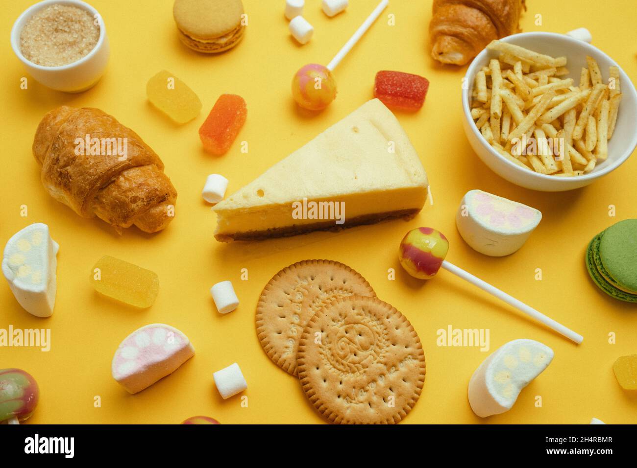 Unhealthy foods. French croissant, candy on a stick, jelly candies, marshmallows, cookies and