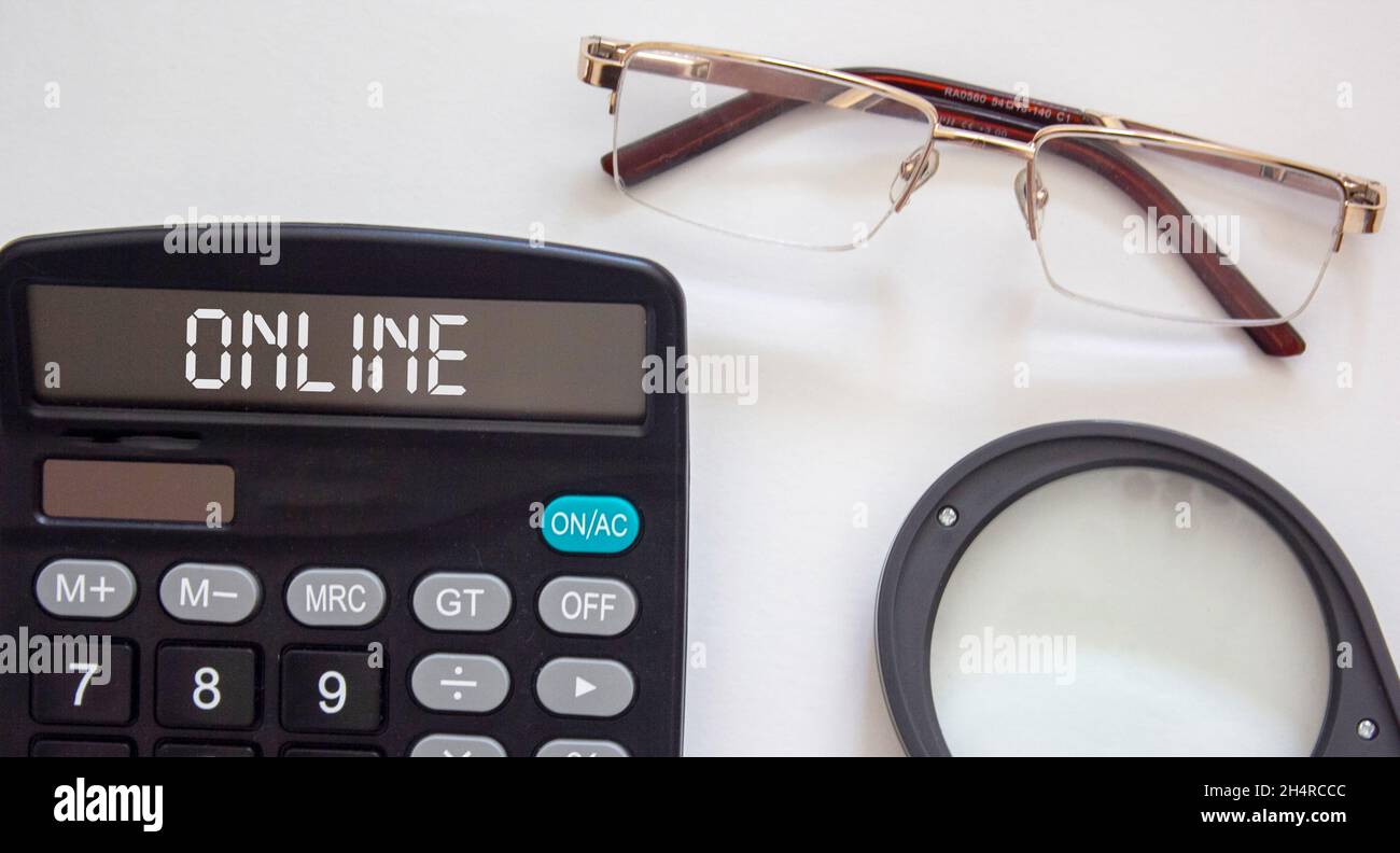 Online text on a calculator, near glasses and a magnifier on a white background Stock Photo
