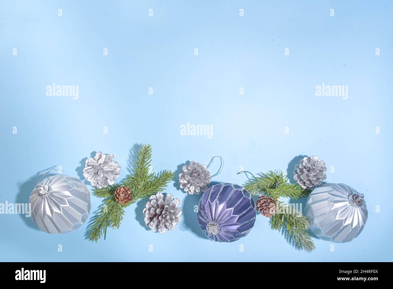 Christmas New Year background. Greeting card, invitation mockup with blue and silver Xmas tree balls, christmas-tree cones on light blue background, f Stock Photo
