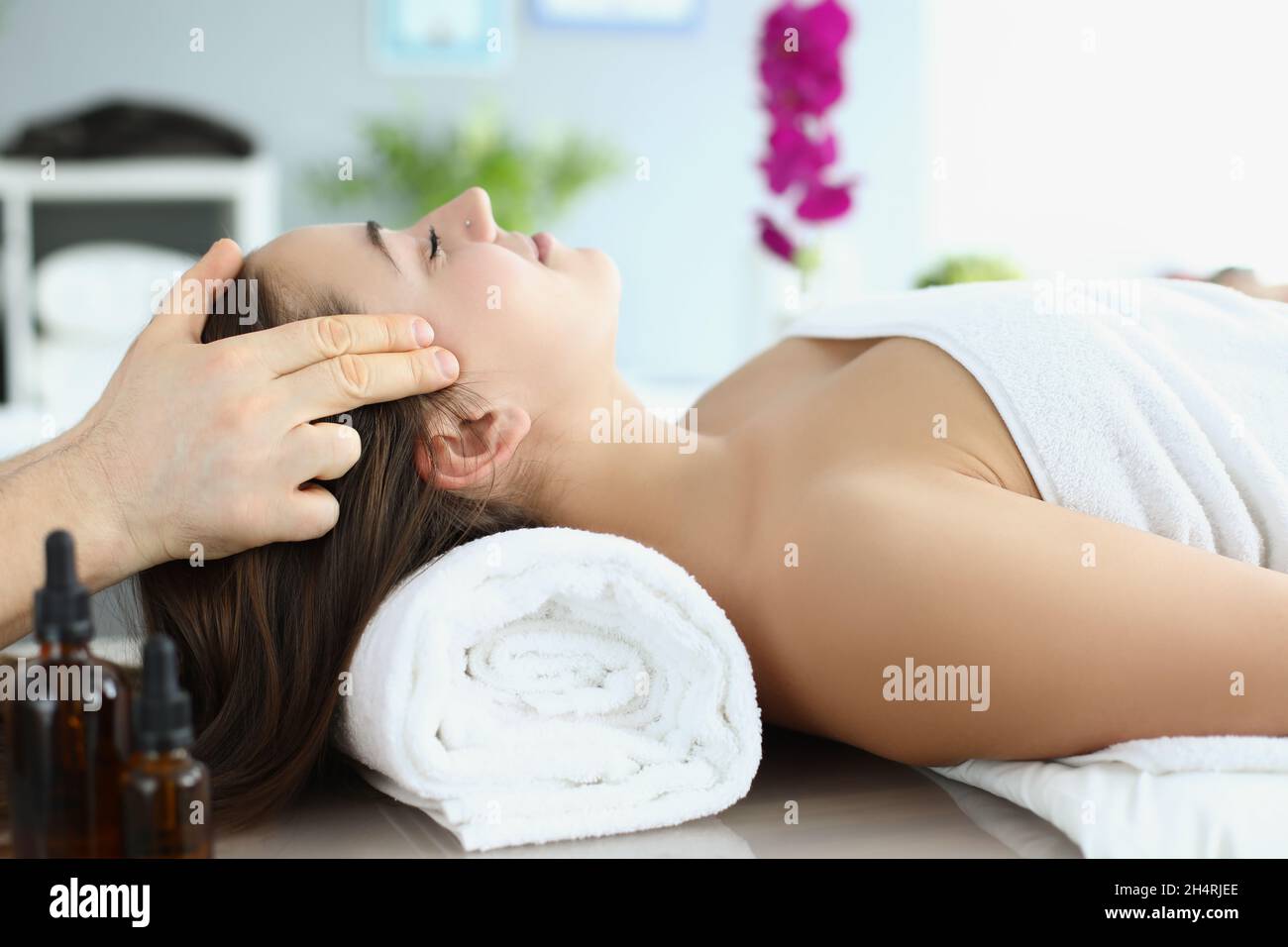 Close-uo of beautiful woman getting face massage in luxury spa, masseuse hands massaging girl with closed eyes at resort spa. Wellness, care, beauty t Stock Photo