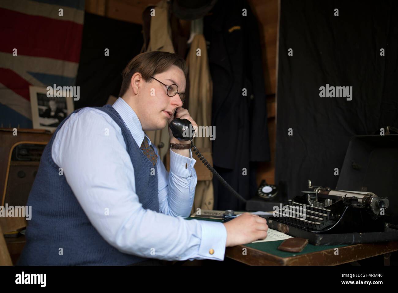 Young civilan man on telephone in voluntary role as ARP warden in 1940s wartime Britain. ARP duties could in administrative and clerical duties. Stock Photo