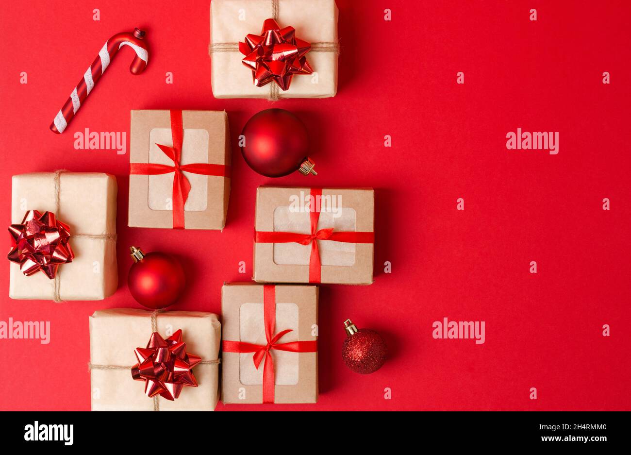 Boxing Day. Christmas gifts in a kraft box and kraft packaging with Christmas decorations on a red background. Christmas background, copying space Stock Photo