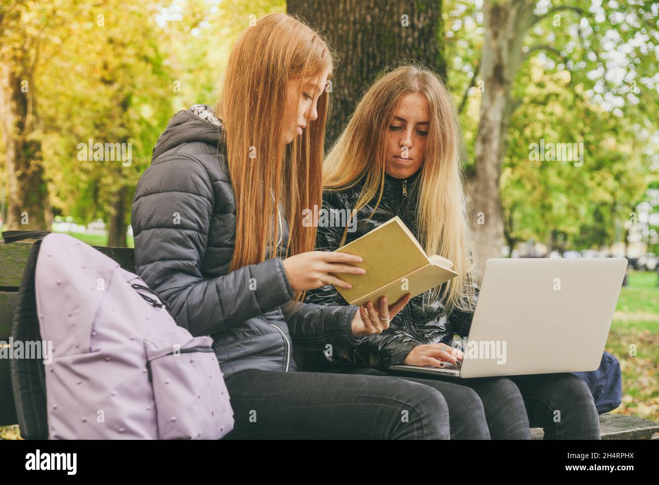 Two girls sitting on park bench hi-res stock photography and images - Alamy