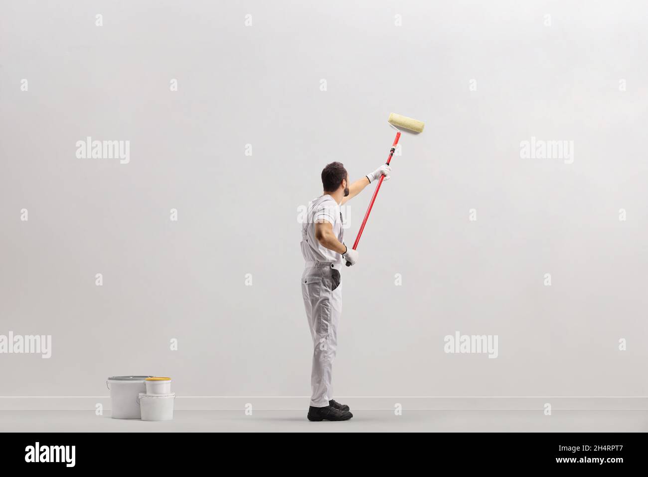 Painter using a paint roller and painting a wall isolated on white background Stock Photo