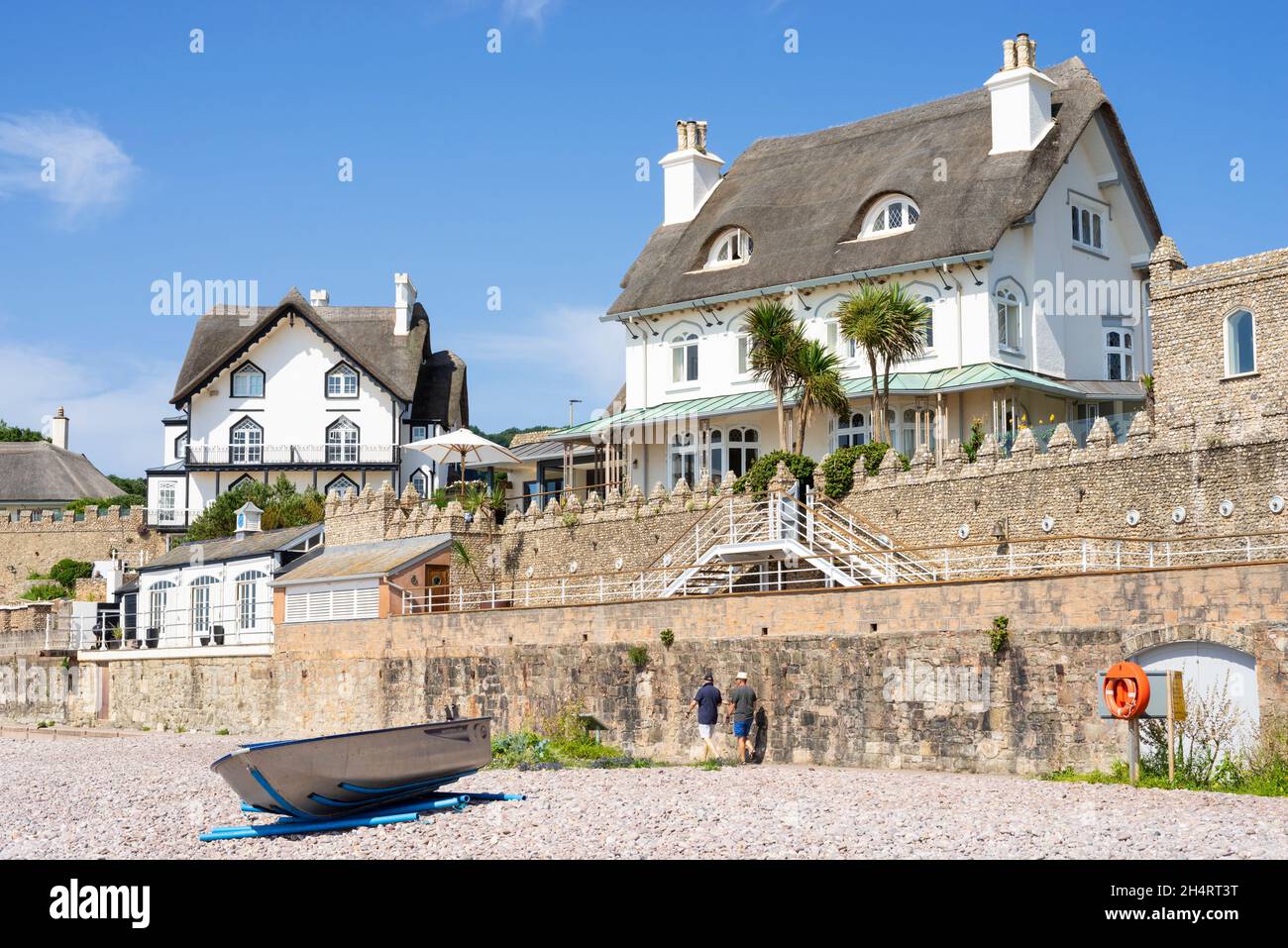 Small boat on the pebble beach under Rock Cottage Hotel and the Beacon Sidmouth Town Sidmouth Devon England UK GB Europe Stock Photo