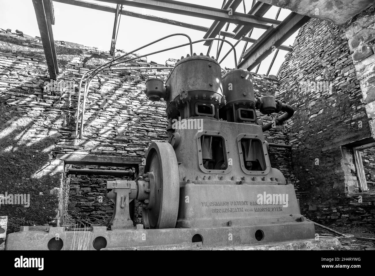Monochrome view of old machinery in derelict, disused slate quarry building, North Wales, UK. Stock Photo