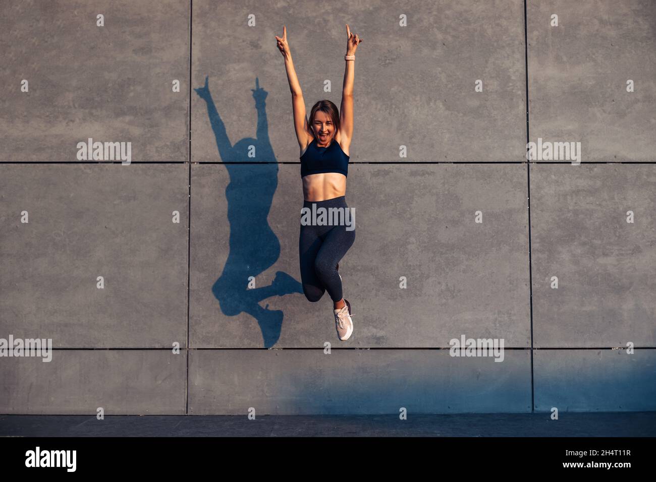 Cheerful positive sportive woman, jumping into the air with raised ...