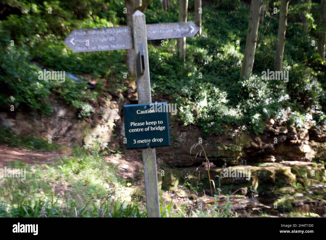Leaning wooden signpost with bridge warning at Cragside, Rothbury ...