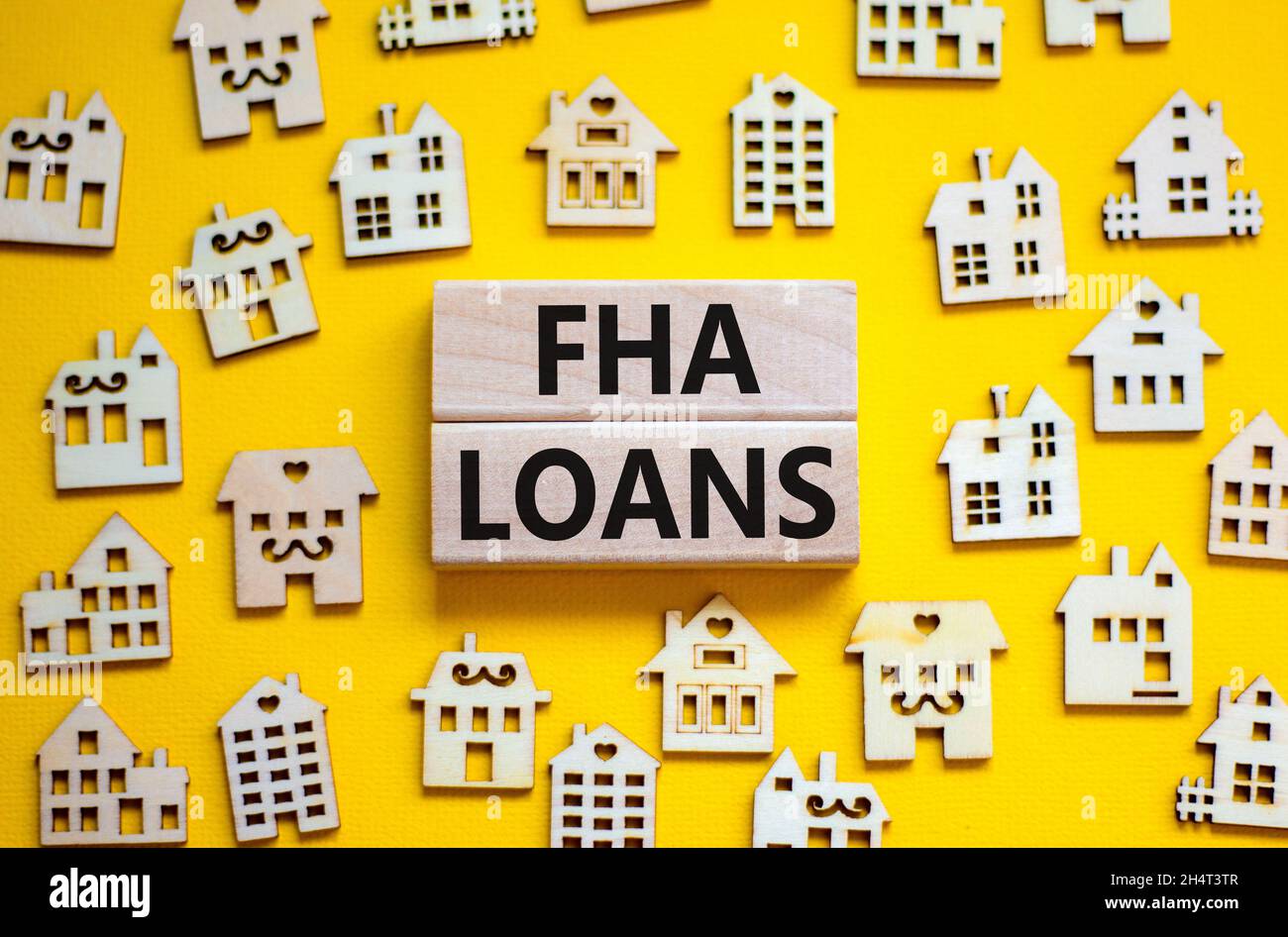 FHA federal housing administration loans symbol. Concept words 'FHA federal housing administration loans' on wooden blocks on a beautiful yellow backg Stock Photo