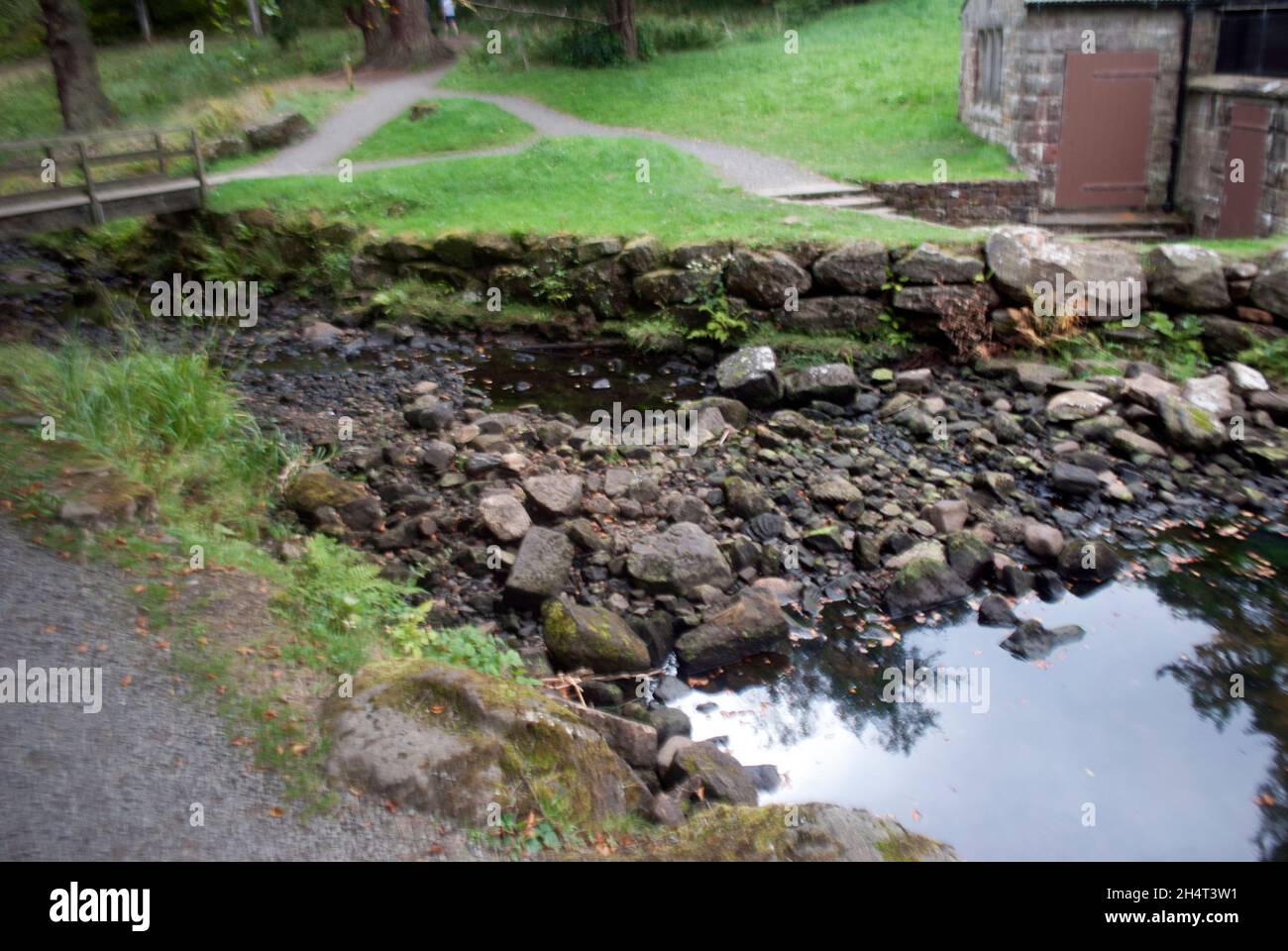 Rocks lake and building near screw turbine at Cragside, Rothbury ...