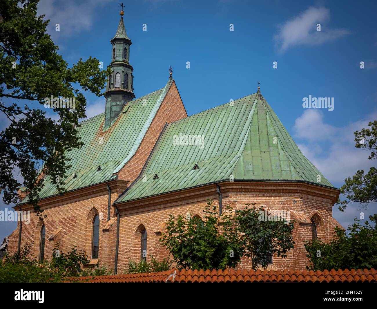 RADOM, POLAND - July 26, 2021: A gothic, medieval church of Saint Waclaw. Brick walls, green roof. Blue sky. Stock Photo