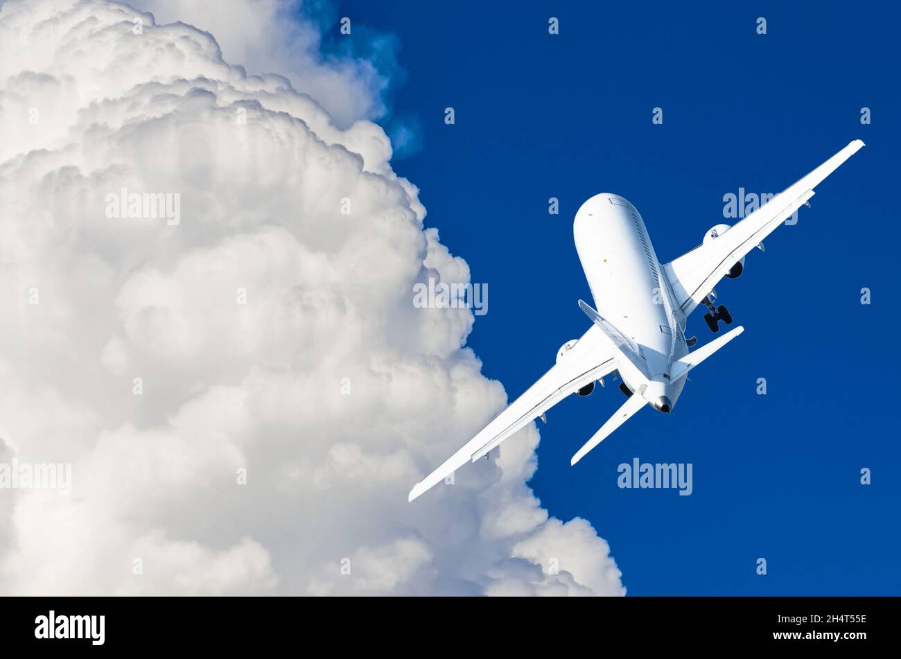 A flying airplane in a blue sky and picturesque clouds Stock Photo - Alamy