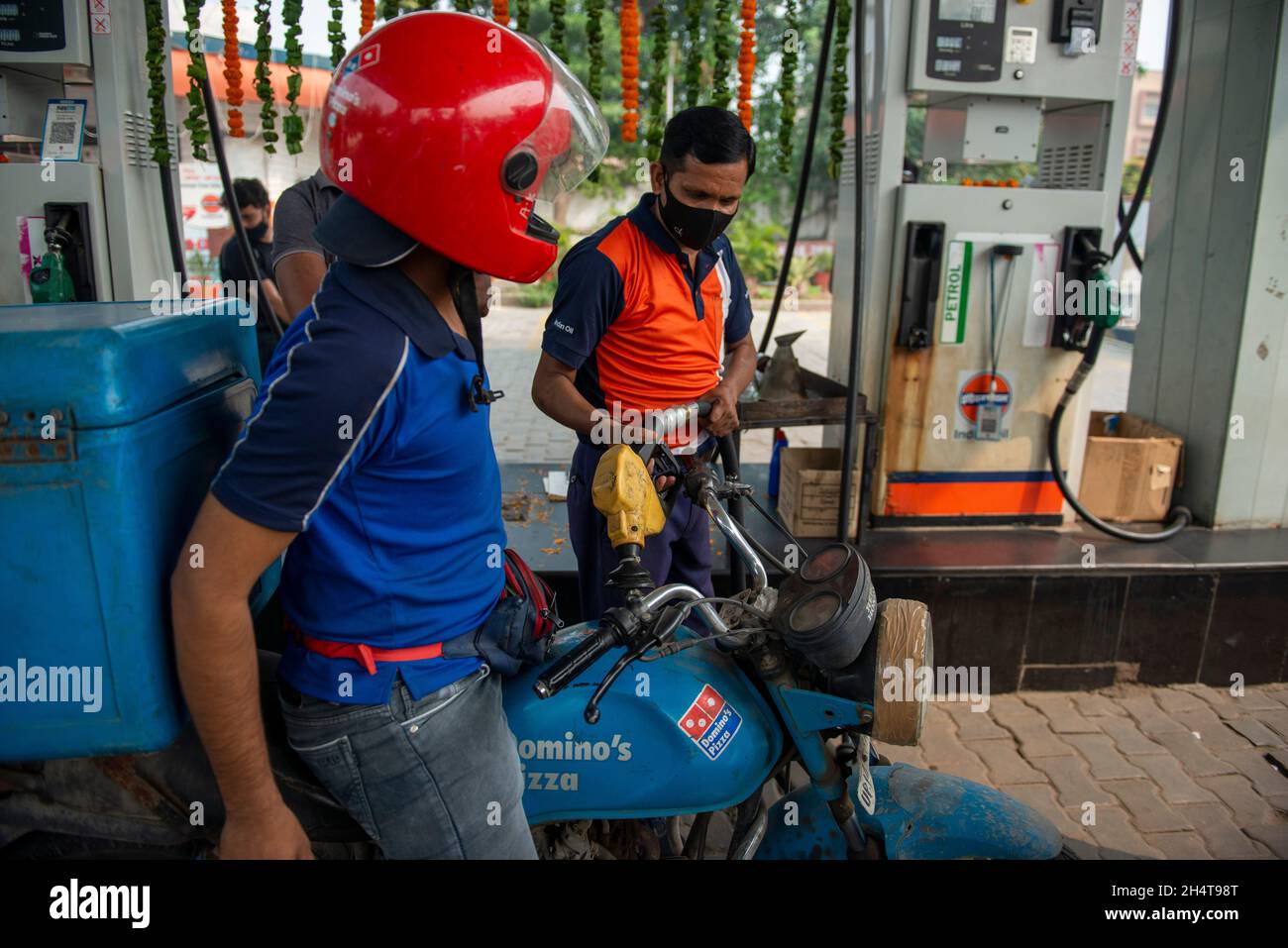 Ghaziabad, India. 04th Nov, 2021. A petrol pump attendant seen refueling a Dominos delivery motor bike at Indian oil petrol pump.Indian Government cuts the excise duty on petrol by Rs 5 (0.067 US Dollar) and on diesel by Rs 10 (0.13 US Dollar) the relief to consumers came on the eve of Diwali. Credit: SOPA Images Limited/Alamy Live News Stock Photo