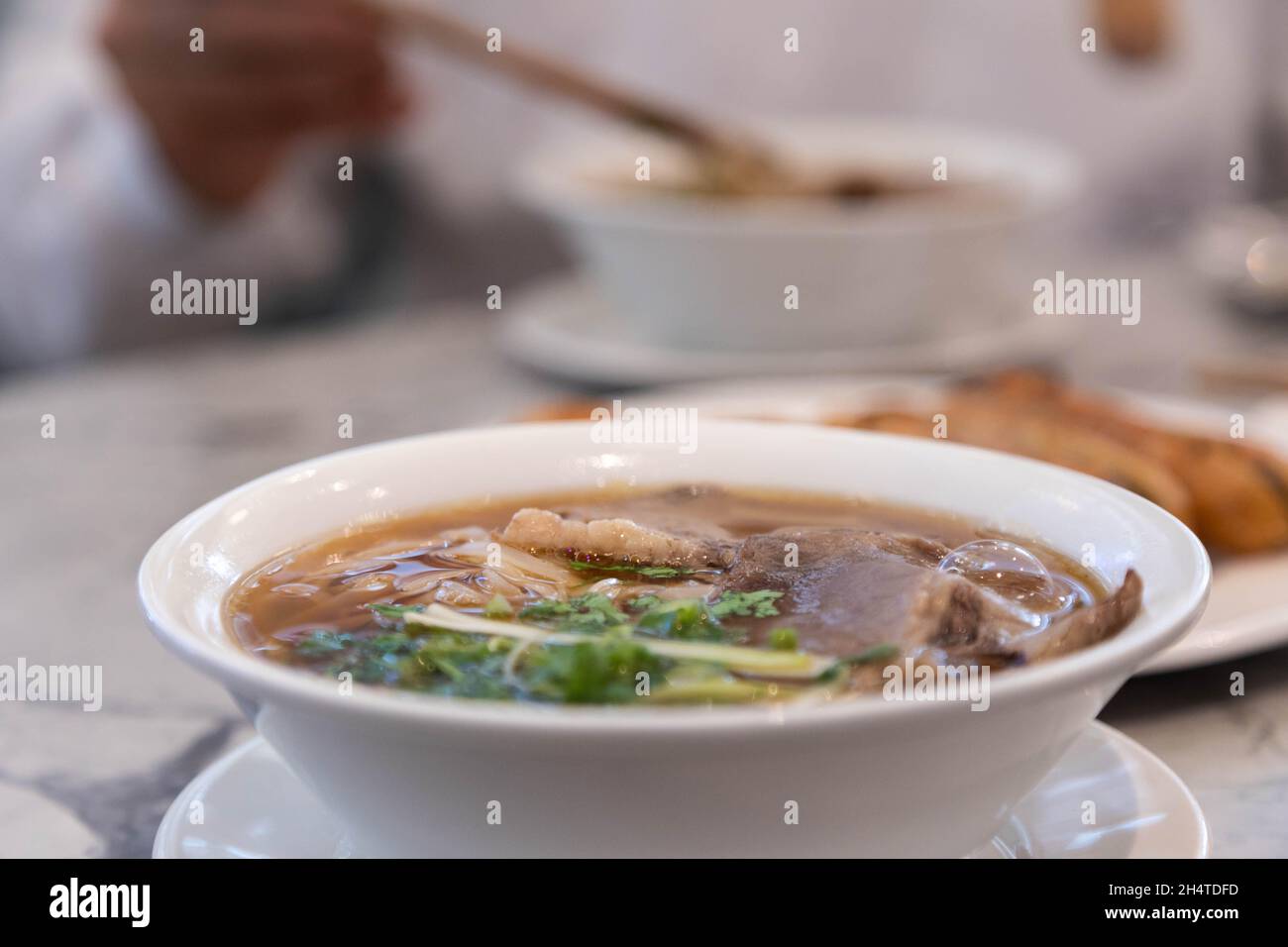 Delicious bowl of pho tai, rich broth, Vietnamese dish, soup, rice noodles. Stock Photo