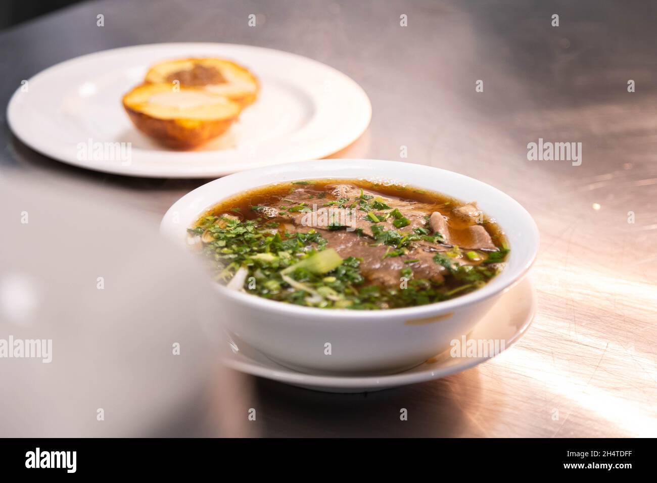 Delicious bowl of pho tai, rich broth, Vietnamese dish, soup, rice noodles. Stock Photo