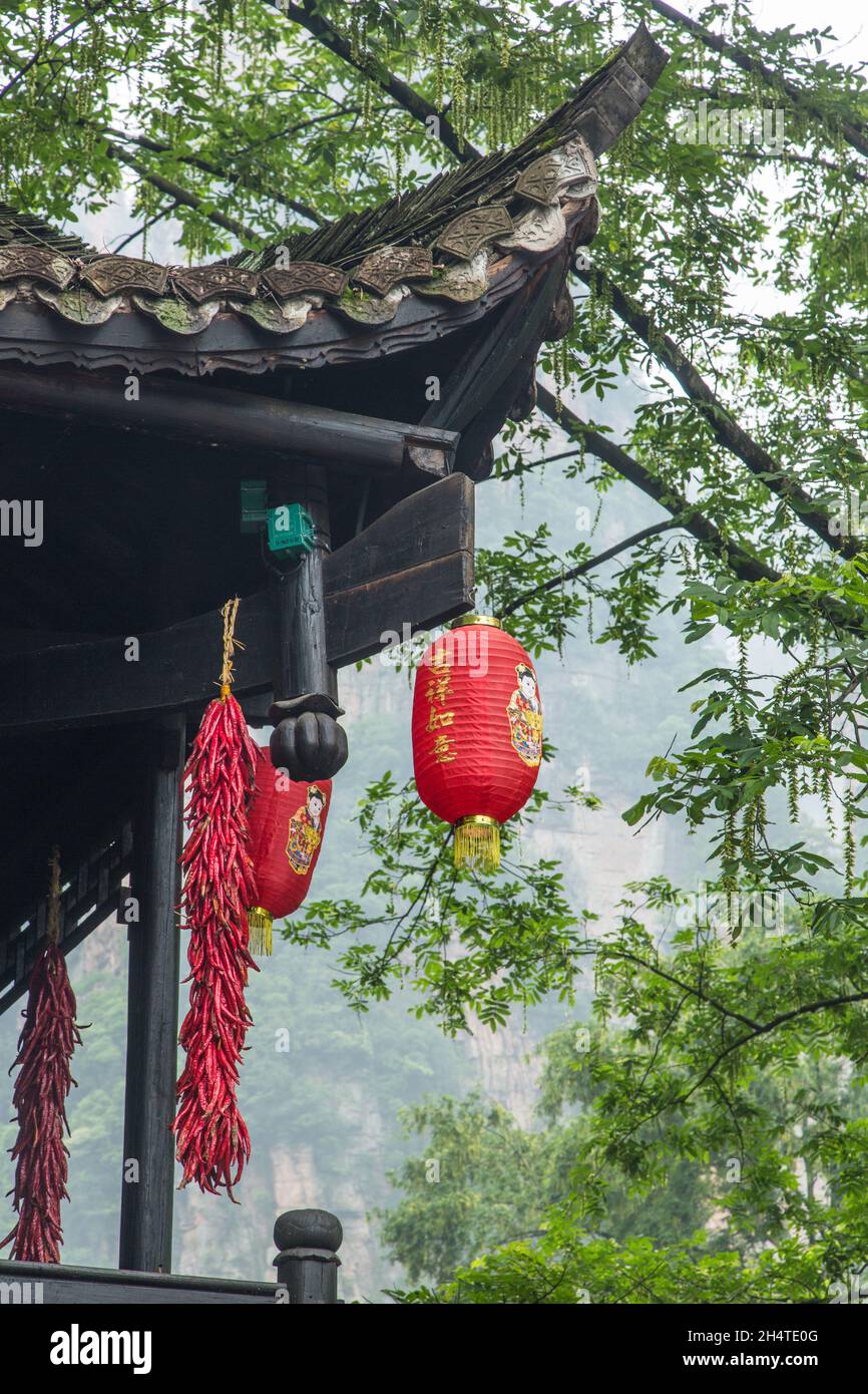 Strands of red chili peppers and Chinese lanterns on a traditional wooden building in Zhangjiajie National Forest Park, Hunan, China. Stock Photo