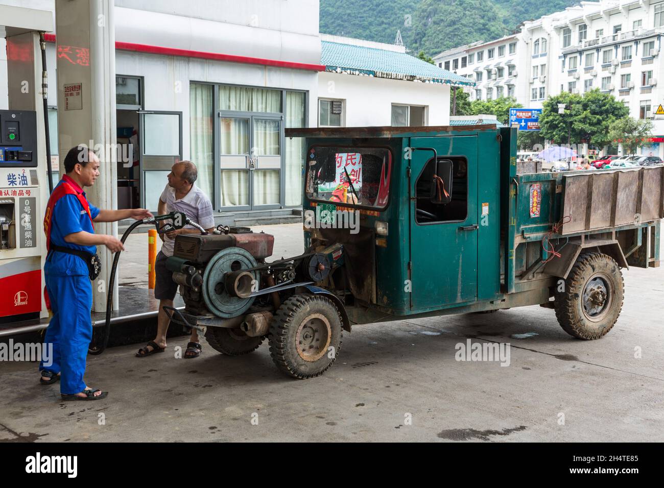 A belt-driven utility tractor-powered farm vehicle being fueled at a gas station in Yangshuo, China. Stock Photo