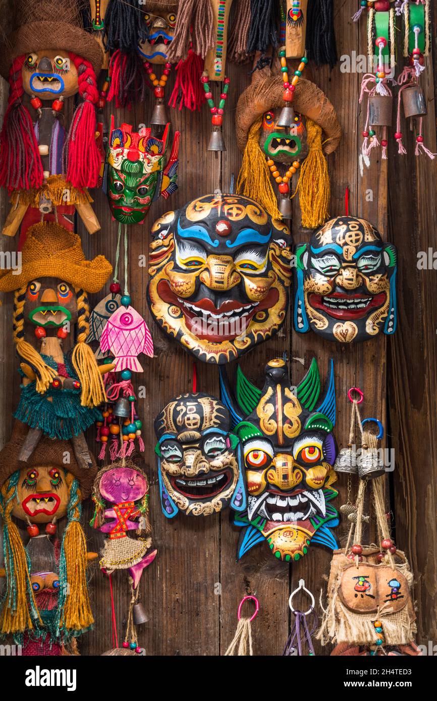 Brightly painted wooden masks and dolls for sale in a souvenir shop in Xingping, China. Stock Photo